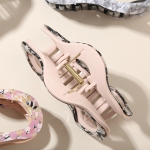 Close-up of patterned acetate claw clip with durable gold metal spring detail