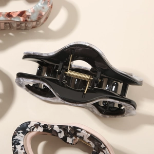 Detail view of large marble texture acetate hair claw clip with golden metal spring