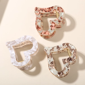 Three elegant heart-shaped acetate hair claws with marble and floral patterns