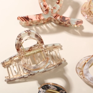 Detailed close-up showing various acetate hair claw clips with marble and amber patterns