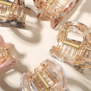 Macro detail of high-quality acetate hair claws with marble patterns and gold metal springs