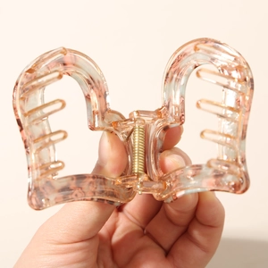 Macro shot of heart-shaped hair claw clip with pink marble texture in hand