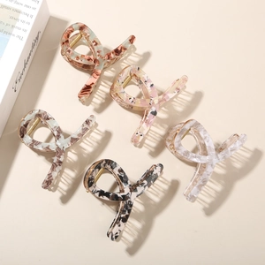 Detail view of five marble acetate hair claws with premium metal springs on a beige background