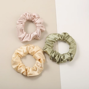Three premium silk-like satin scrunchies in pink, champagne gold, and sage green