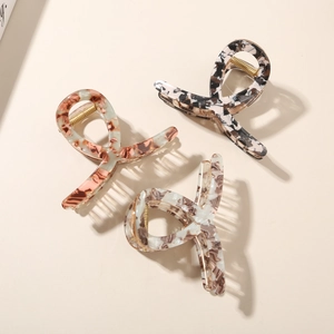 Detailed close-up of marble acetate hair claws with premium metal springs in three colors