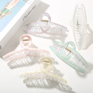 Five pieces of large acetate hair claw clips in pastel marble colors on white surface