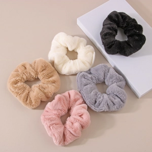 Macro shot of five plush faux rabbit fur scrunchies in neutral colors and soft texture