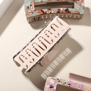Détail de pinces à cheveux rectangulaires en acétate avec motifs marbrés et finition lisse