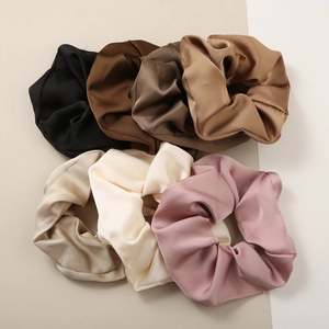 Close-up of six silky oversized hair scrunchies in elegant neutral colors for women