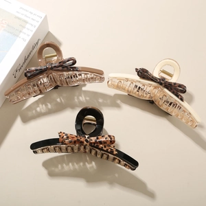 Detailed view of acetate hair claws with leopard print bows in black, cream, and brown