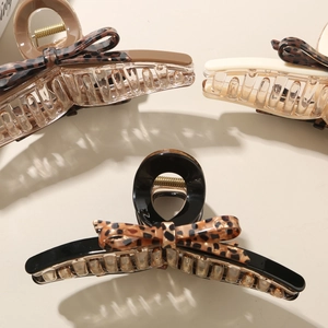 Detailed view of three acetate leopard print bow hair claws in black, cream, and brown