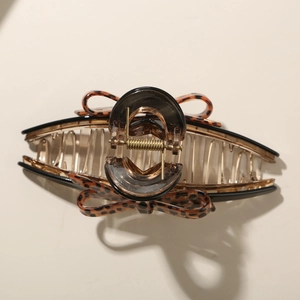 Detailed close-up of leopard print bow hair claw clip with golden metal spring