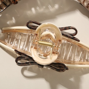 Detail of large acetate hair claw clip featuring leopard bow and strong gold spring mechanism