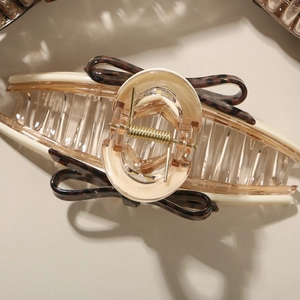 Macro detail of leopard print bow hair claw clip with golden spring and resin teeth