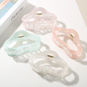Close-up of four iridescent wavy hair claws in pink, peach, mint green, and pearl white
