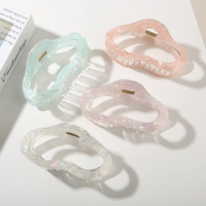 Detailed overhead view of four iridescent pastel acetate cloud hair claws on white background