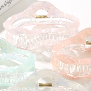 Close-up of wavy iridescent acetate hair claws in pastel pink and mint green