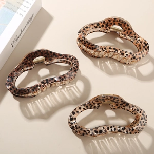 Close-up of three leopard print hair claws in brown and beige tones with metal springs