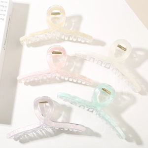 Close-up of five pearlescent hair claws in pastel colors with gold metal springs