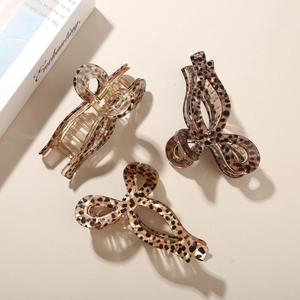Three acetate hair claws with leopard print pattern in warm amber tones on a beige background
