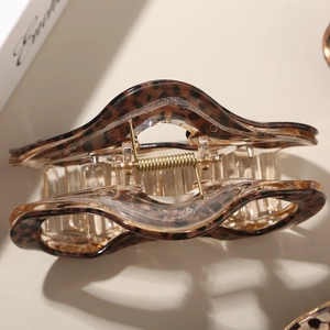 Macro shot of amber leopard print hair claw clip with a glossy finish and gold metal spring