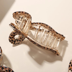 Macro view of translucent amber leopard print hair claw clip with metallic spring mechanism