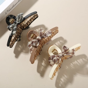 Detail of elegant acetate checkered bow hair claws in black, brown and beige colors