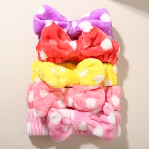 Detailed stack of five colorful plush polka dot bow headbands in vibrant coral fleece fabric
