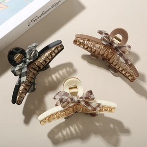 Detailed set of acetate bow hair claws in black, caramel brown, and cream white colors