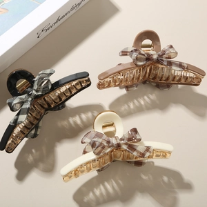 Detail view of acetate claw clips with checkered fabric bows in black, brown and beige colors