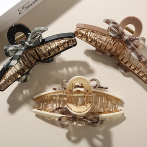 Close-up of three elegant plaid bow claw clips in black, mocha and cream colors