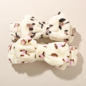 Detail of two plush coral fleece bow headbands with leopard and polka dot patterns