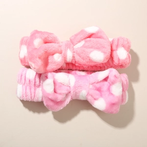 Detail showing two pink plush polka dot headbands with large bows for skincare