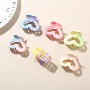 Detail of six heart-shaped gradient hair claws with white speckle patterns on beige base