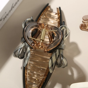 Detail view of acetate bow hair claw clip with amber resin finish and checkered fabric