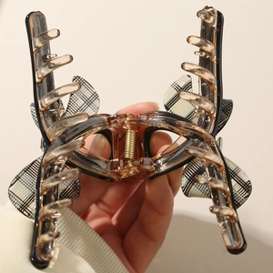 Elegant acetate amber bow hair claw clip with checkered pattern wings and gold spring