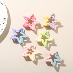 Set of six colorful gradient star-shaped hair claws with matte texture on beige surface