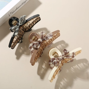 Detailed view of acetic acid hair claws with checkered fabric bows in black and cream