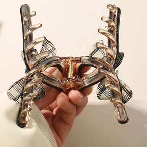 Detail of large amber resin hair claw clip with black and white checkered bow ornament