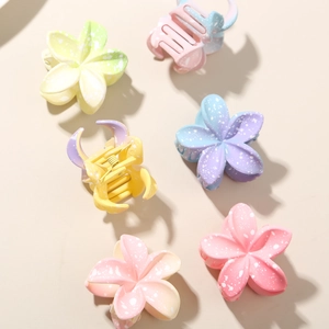 Detail view of colorful gradient plumeria flower hair clips with matte finish texture