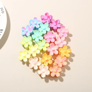 Macro detail of colorful 2.5cm petal hair claws arranged in a heart shape on a soft beige base