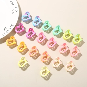 Macro display of 18 heart-shaped macaron hair clips in an organized array on beige surface