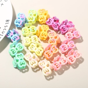 Mini macaron bow hair clips arranged in a heart shape on a beige background