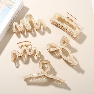 Detailed set of five acetate hair claws in creamy marble patterns on a beige background