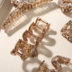 Detailed macro view of acetate hair claws with premium amber marble texture patterns
