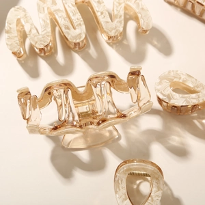 Close-up of large acetate claw clips in amber and marble textures with golden springs