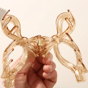 Close-up of large bow-shaped hair claw clip in amber acetate with gold metal spring