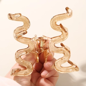 Detailed view of an amber cellulose acetate hair claw clip with strong gold metal spring