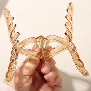 Detail showing high-quality amber-colored large claw clip with gold metal spring for thick hair