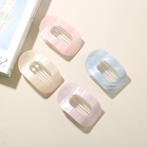 Détail de quatre pinces à cheveux ovales aux tons rose, blanc, bleu et violet nacré